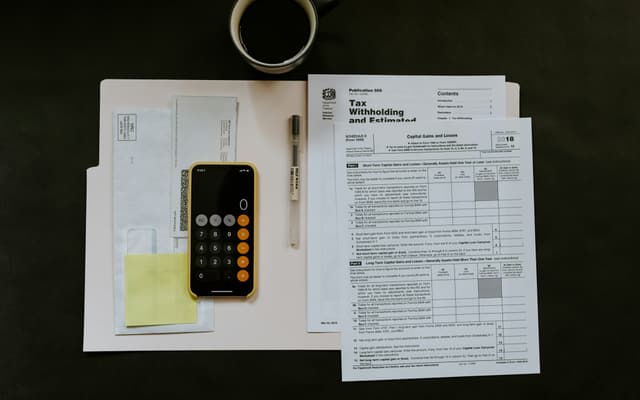 A person reviewing paperwork and a calculator