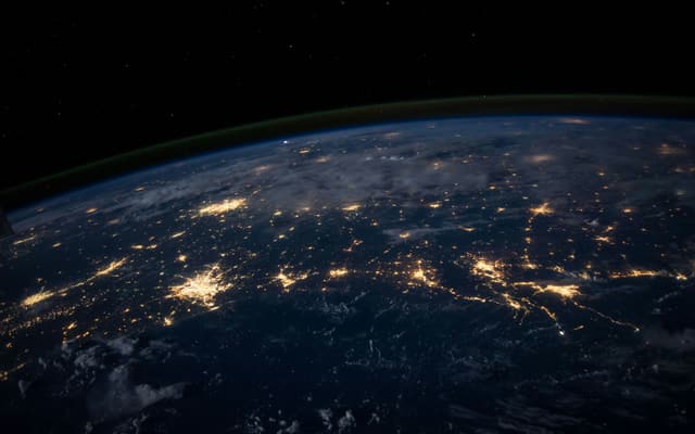 The Earth at night seen from orbit, city lights visible